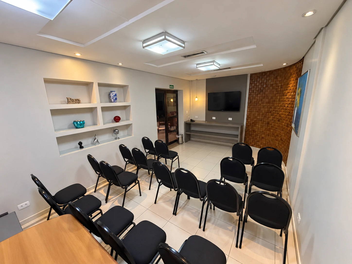 Sala de reunião do Brumado Hotel com cadeiras, TV de tela plana e ar-condicionado