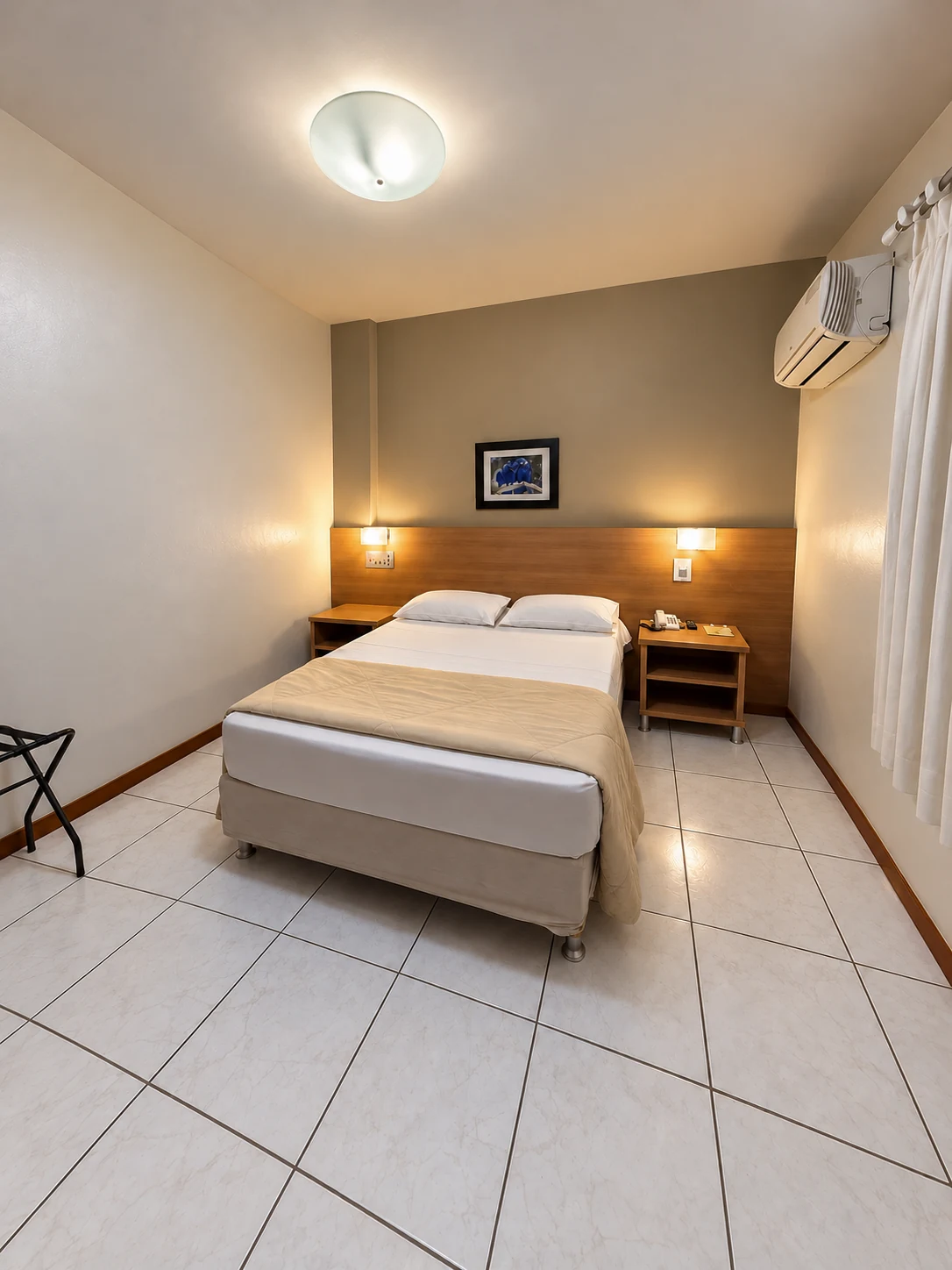 Quarto Standard com cama de casal, cabeceira de madeira, cortinas e ar-condicionado
